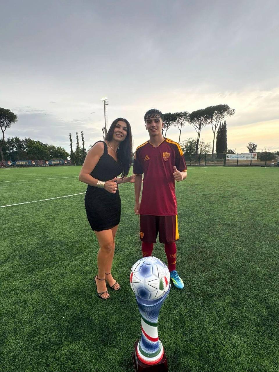 Souhaila Mia sul campo con un giovane calciatore della Roma e il trofeo Scopigno Cup